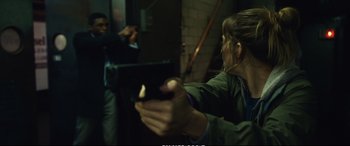 Movie still from “21 Bridges” (2019), directed by Brian Kirk – A woman holding a video game controller in her hands; Medium shot, Over the shoulder angle