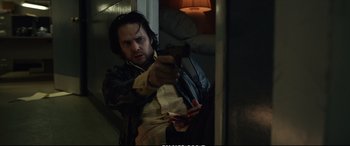 Movie still from “21 Bridges” (2019), directed by Brian Kirk – A man holding a gun in a room; Medium shot, Low angle
