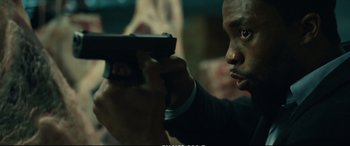 Movie still from “21 Bridges” (2019), directed by Brian Kirk – A person holding a gun; Close Up shot, Over the shoulder angle