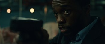 Movie still from “21 Bridges” (2019), directed by Brian Kirk – A person using a cell phone; Close Up shot, Over the shoulder angle