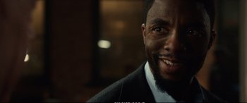 Movie still from “21 Bridges” (2019), directed by Brian Kirk – A person wearing a suit and tie; Close Up shot, Over the shoulder angle