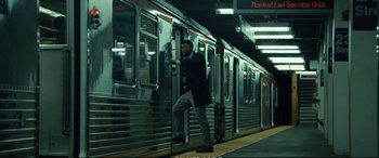 Movie still from “21 Bridges” (2019), directed by Brian Kirk – A man standing on the side of a subway train; Wide shot, High angle