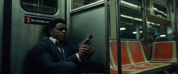 Movie still from “21 Bridges” (2019), directed by Brian Kirk – A man sitting on a train holding a gun in his hand; Medium shot, Low angle