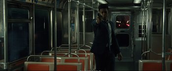 Movie still from “21 Bridges” (2019), directed by Brian Kirk – A man in a suit and tie holding a gun; Medium shot, Over the shoulder angle