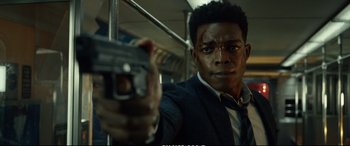 Movie still from “21 Bridges” (2019), directed by Brian Kirk – A man holding a gun on top of a train; Close Up shot, Low angle