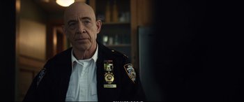 Movie still from “21 Bridges” (2019), directed by Brian Kirk – A man in a police uniform is standing in front of a bookshelf; Close Up shot, Over the shoulder angle