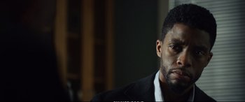 Movie still from “21 Bridges” (2019), directed by Brian Kirk – A person wearing a suit and tie; Close Up shot, Low angle