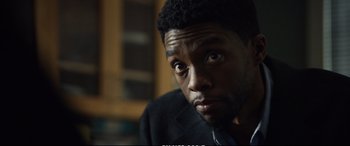 Movie still from “21 Bridges” (2019), directed by Brian Kirk – A person wearing a suit and tie; Close Up shot, Over the shoulder angle
