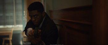 Movie still from “21 Bridges” (2019), directed by Brian Kirk – A man holding a remote in his hand; Medium shot, High angle