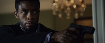Movie still from “21 Bridges” (2019), directed by Brian Kirk – A person wearing a suit and tie; Close Up shot, Over the shoulder angle