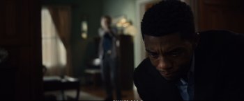 Movie still from “21 Bridges” (2019), directed by Brian Kirk – A man in a black shirt is looking at a woman in a black dress; Close Up shot, Over the shoulder angle