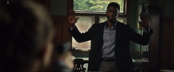 Movie still from “21 Bridges” (2019), directed by Brian Kirk – A man in a black jacket is waving at the camera; Medium shot, Over the shoulder angle