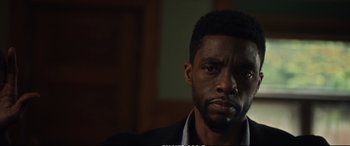 Movie still from “21 Bridges” (2019), directed by Brian Kirk – A person wearing a suit and tie; Close Up shot, Over the shoulder angle
