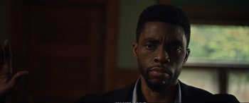 Movie still from “21 Bridges” (2019), directed by Brian Kirk – A person wearing a suit and tie; Close Up shot, Low angle