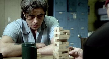 Movie still from “21 Grams” (2003), directed by Alejandro G. Iñárritu – A man playing a game of jenga on a table; Close Up shot, Over the shoulder angle
