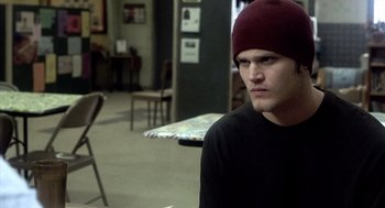 Movie still from “21 Grams” (2003), directed by Alejandro G. Iñárritu – A man wearing a red hat sitting in a room; Close Up shot, Over the shoulder angle