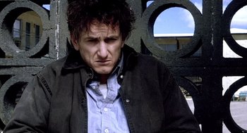 Movie still from “21 Grams” (2003), directed by Alejandro G. Iñárritu – A man in a black jacket is looking sad; Close Up shot, Low angle