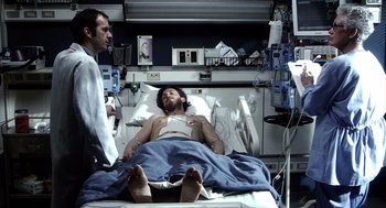 Movie still from “21 Grams” (2003), directed by Alejandro G. Iñárritu – A man in a hospital bed talking to a doctor; Medium shot, Over the shoulder angle