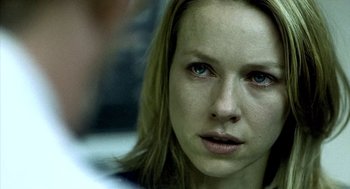 Movie still from “21 Grams” (2003), directed by Alejandro G. Iñárritu – A woman's face in a dark room; Close Up shot, Over the shoulder angle