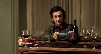 Movie still from “21 Grams” (2003), directed by Alejandro G. Iñárritu – A man sitting at a table with a knife in his hand; Medium shot, Over the shoulder angle