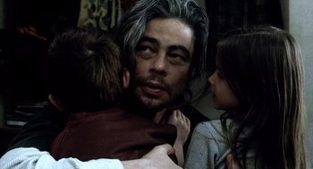 Movie still from “21 Grams” (2003), directed by Alejandro G. Iñárritu – A man with long grey hair is hugging two children; Close Up shot, Over the shoulder angle
