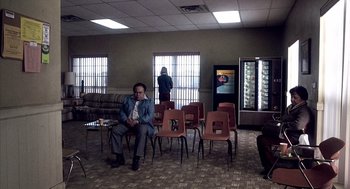 Movie still from “21 Grams” (2003), directed by Alejandro G. Iñárritu – A man sitting on a chair in a room; Wide shot, High angle