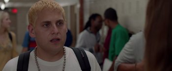 Movie still from “21 Jump Street” (2012), directed by Phil Lord – A man with a beard and a white t - shirt is in a hallway; Close Up shot, Over the shoulder angle