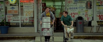 Movie still from “21 Jump Street” (2012), directed by Phil Lord – Two men pushing a shopping cart full of food; Wide shot, High angle