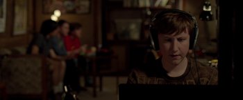 Movie still from “21 Jump Street” (2012), directed by Phil Lord – A person with headphones on sitting in a room; Medium shot, Over the shoulder angle