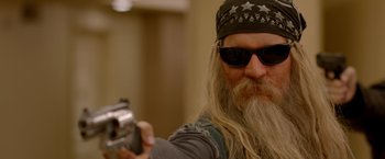 Movie still from “21 Jump Street” (2012), directed by Phil Lord – A man with long hair and a beard is holding a gun; Close Up shot, Over the shoulder angle