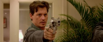 Movie still from “21 Jump Street” (2012), directed by Phil Lord – A man holding a gun pointed at the camera; Close Up shot, Over the shoulder angle