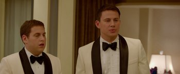 Movie still from “21 Jump Street” (2012), directed by Phil Lord – A man in a white suit with a black bow tie; Close Up shot, Over the shoulder angle