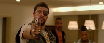 Movie still from “21 Jump Street” (2012), directed by Phil Lord – A man with a eye patch holding a gun in front of another man; Close Up shot, Over the shoulder angle