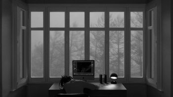 Movie still from “24 Frames” (2017), directed by Abbas Kiarostami – A person sitting in front of a computer in front of a window; Wide shot, High angle