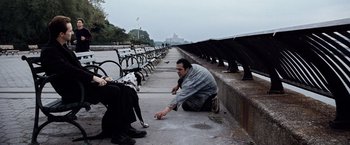 Movie still from “25th Hour” (2002), directed by Spike Lee – A man kneeling on the ground next to a bench; Wide shot, Over the shoulder angle