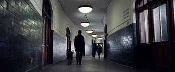 Movie still from “25th Hour” (2002), directed by Spike Lee – A man and a dog walking down a hall way; Wide shot, Low angle