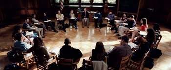 Movie still from “25th Hour” (2002), directed by Spike Lee – A group of people sitting in a circle in front of a window; Wide shot, High angle