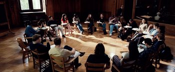 Movie still from “25th Hour” (2002), directed by Spike Lee – A group of people sitting in a circle in a room; Wide shot, High angle