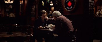 Movie still from “25th Hour” (2002), directed by Spike Lee – Two men sitting at a table in front of drinks; Medium shot, Over the shoulder angle