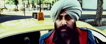 Movie still from “25th Hour” (2002), directed by Spike Lee – A man with a beard and a turban in front of a yellow taxi cab; Close Up shot, Low angle