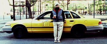 Movie still from “25th Hour” (2002), directed by Spike Lee – A man standing in front of a yellow taxi cab; Wide shot, Overhead angle