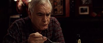Movie still from “25th Hour” (2002), directed by Spike Lee – An older man sitting at a table holding a spoon; Close Up shot, High angle