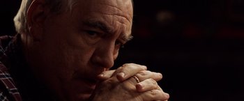 Movie still from “25th Hour” (2002), directed by Spike Lee – An older man with his hands clasped in front of his face; Close Up shot, High angle
