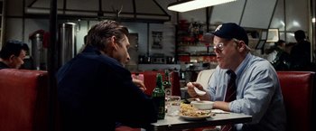 Movie still from “25th Hour” (2002), directed by Spike Lee – Two men sitting at a table with food and drinks; Medium shot, Over the shoulder angle