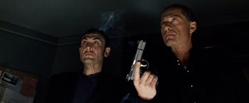 Movie still from “25th Hour” (2002), directed by Spike Lee – Two men are holding guns in a dark room; Close Up shot, Low angle
