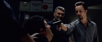 Movie still from “25th Hour” (2002), directed by Spike Lee – A man holding a gun pointed at another man with a gun; Medium shot, Over the shoulder angle