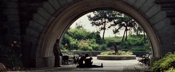 Movie still from “25th Hour” (2002), directed by Spike Lee – Two people sitting on the ground under an archway; Wide shot, Over the shoulder angle