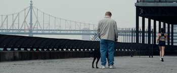 Movie still from “25th Hour” (2002), directed by Spike Lee – A man and a dog stand on the sidewalk; Wide shot, Over the shoulder angle