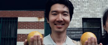 Movie still from “25th Hour” (2002), directed by Spike Lee – A man holding an orange in front of a brick wall; Close Up shot, Overhead angle
