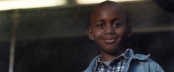 Movie still from “25th Hour” (2002), directed by Spike Lee – A young boy smiles for the camera; Close Up shot, High angle